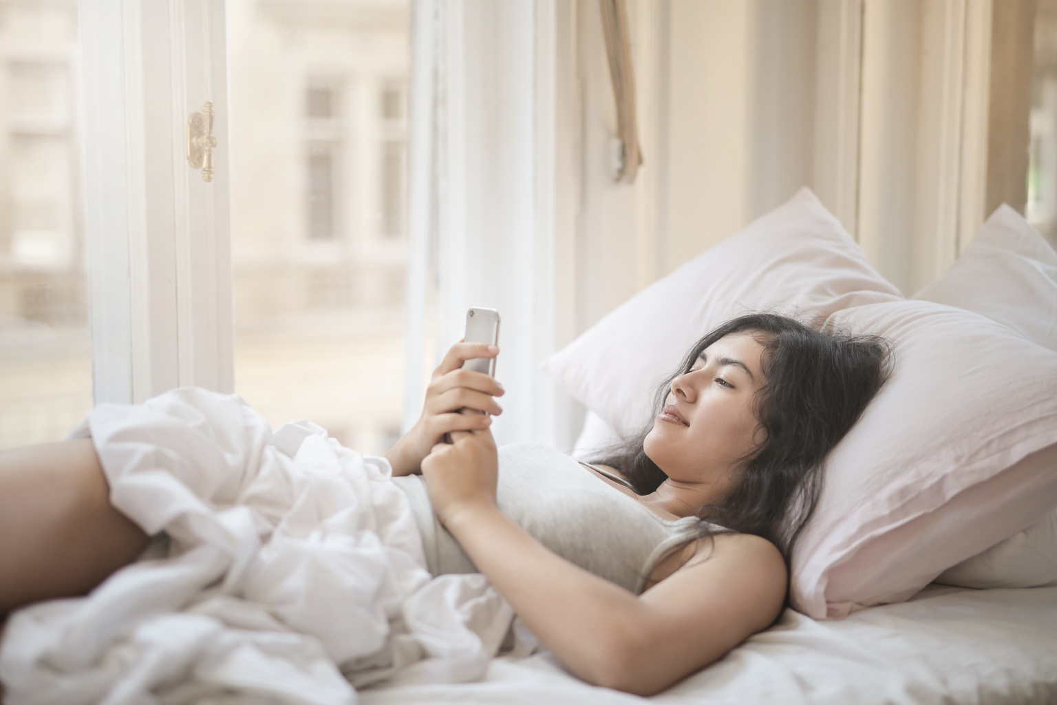 Young woman using smartphone in bed